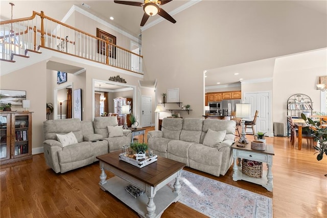 living room featuring crown molding, wood-type flooring, and a high ceiling