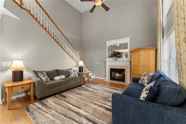 living room with a high ceiling, ceiling fan, and light hardwood / wood-style floors