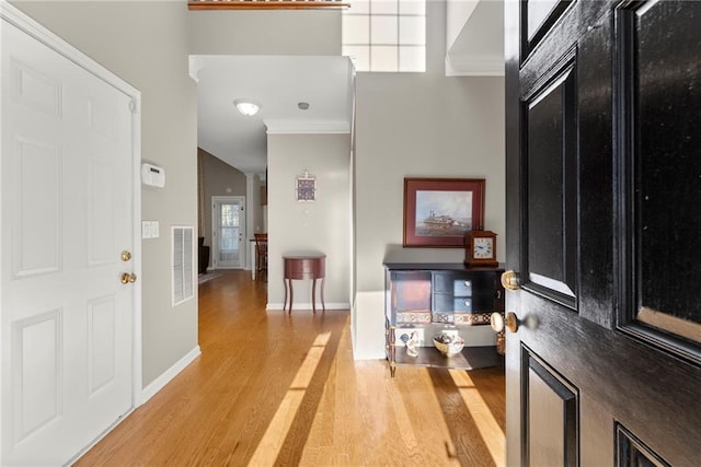 entrance foyer with ornamental molding and light hardwood / wood-style floors