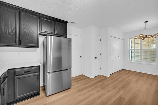 kitchen featuring a chandelier, stainless steel fridge, decorative light fixtures, and light hardwood / wood-style flooring