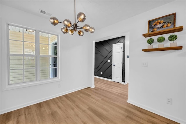 unfurnished dining area featuring an inviting chandelier and light wood-type flooring