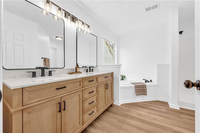 bathroom with vanity, hardwood / wood-style floors, and a bathtub