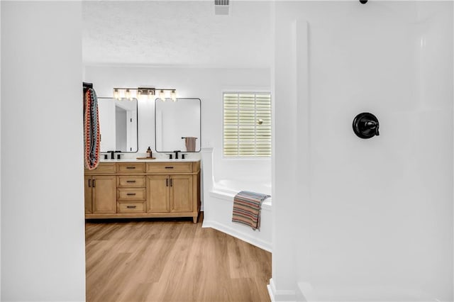 bathroom with a bath, vanity, hardwood / wood-style floors, and a textured ceiling