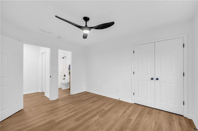 unfurnished bedroom featuring light hardwood / wood-style flooring, a closet, ceiling fan, and ensuite bathroom