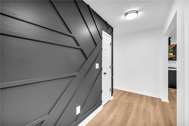 hall with a textured ceiling and light hardwood / wood-style floors