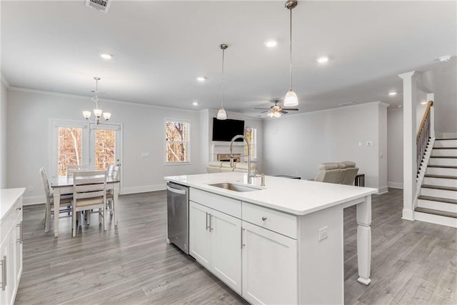 kitchen with a kitchen island with sink, sink, decorative light fixtures, dishwasher, and white cabinetry