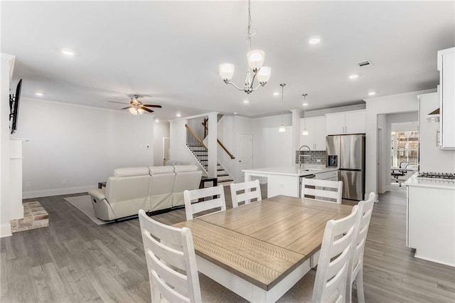 dining room with hardwood / wood-style floors, ceiling fan with notable chandelier, and sink