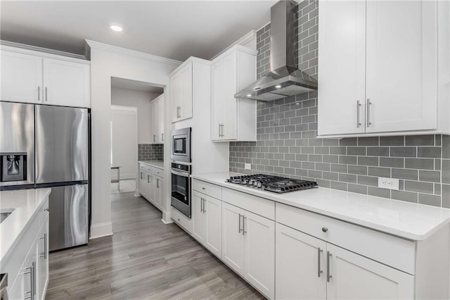 kitchen with decorative backsplash, wall chimney exhaust hood, stainless steel appliances, crown molding, and white cabinetry