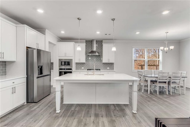 kitchen featuring pendant lighting, wall chimney exhaust hood, appliances with stainless steel finishes, and tasteful backsplash