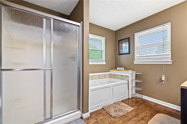 full bath with baseboards, a garden tub, wood finished floors, and a shower stall