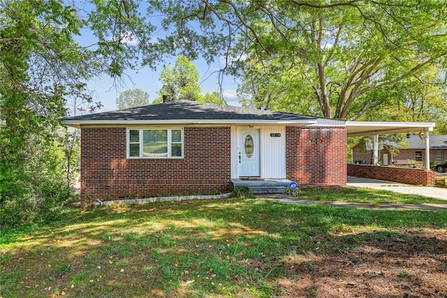 view of front facade with brick siding, a front lawn, an attached carport, and concrete driveway