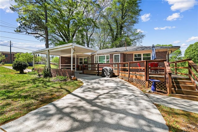 view of front of home with a wooden deck, a front lawn, and brick siding