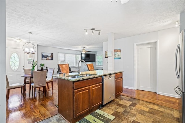 kitchen with a sink, a textured ceiling, brown cabinets, and stainless steel appliances