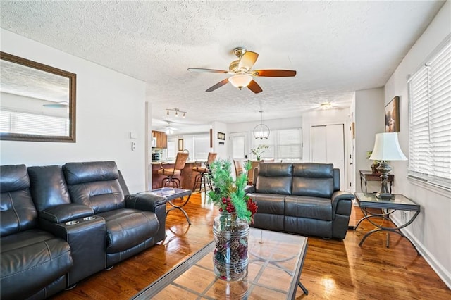 living room with a ceiling fan, a textured ceiling, wood finished floors, and a healthy amount of sunlight