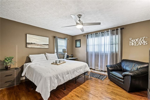 bedroom with a ceiling fan, a textured ceiling, and wood finished floors