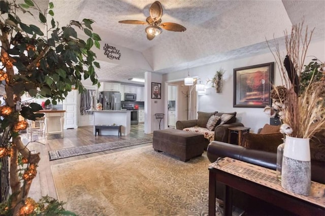 living room with lofted ceiling, ceiling fan, wood-type flooring, and a textured ceiling