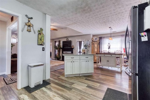 kitchen with pendant lighting, stainless steel fridge, and hardwood / wood-style flooring