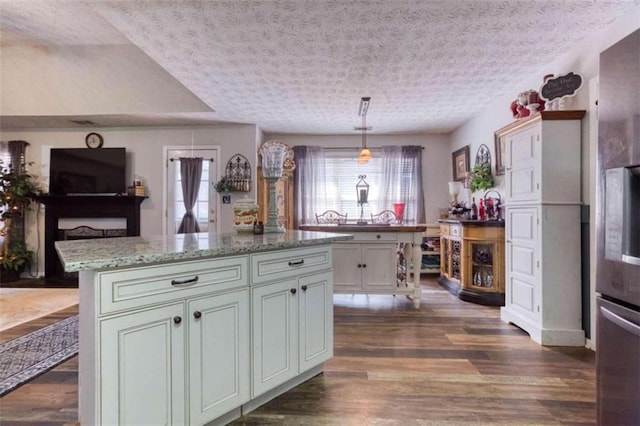 kitchen featuring plenty of natural light, dark wood-type flooring, a center island, and light stone countertops