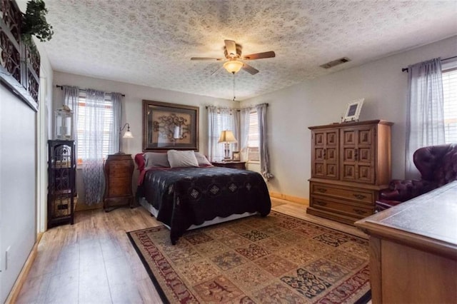 bedroom featuring hardwood / wood-style floors, ceiling fan, and a textured ceiling