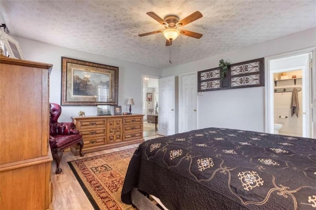 bedroom with a textured ceiling, light hardwood / wood-style flooring, connected bathroom, and ceiling fan