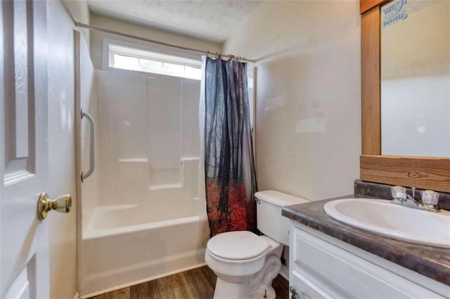 full bathroom with shower / bath combo, hardwood / wood-style floors, toilet, vanity, and a textured ceiling