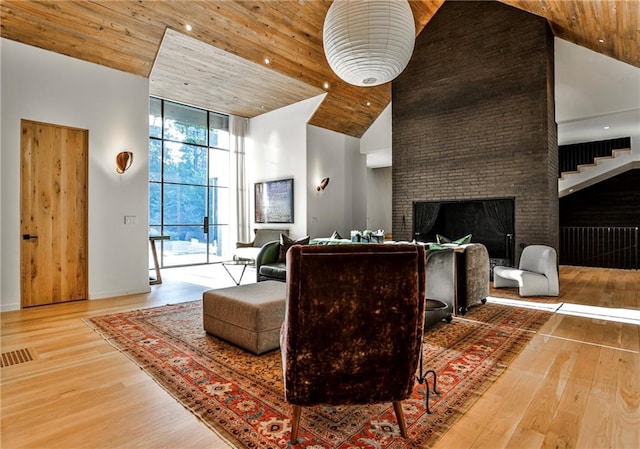 living room featuring floor to ceiling windows, wood ceiling, a large fireplace, wood-type flooring, and high vaulted ceiling