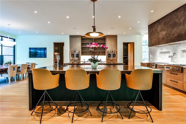 kitchen featuring a breakfast bar, a large island with sink, appliances with stainless steel finishes, and pendant lighting