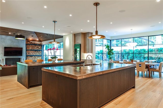 kitchen featuring sink, pendant lighting, a spacious island, light hardwood / wood-style floors, and dark brown cabinets