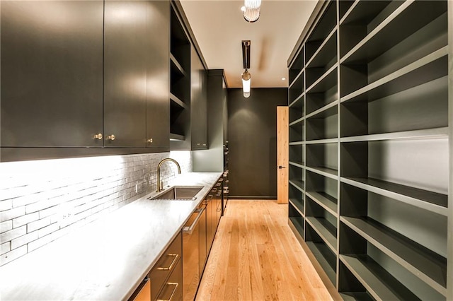 interior space featuring light stone countertops, backsplash, light hardwood / wood-style flooring, and sink