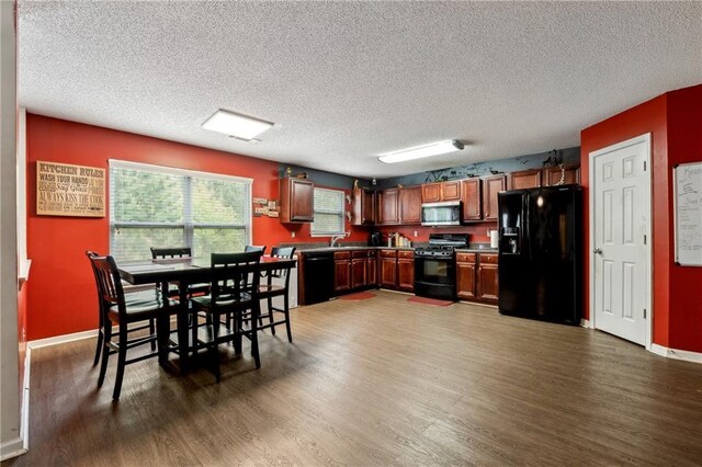 kitchen with baseboards, dark wood-style flooring, a textured ceiling, black appliances, and a sink