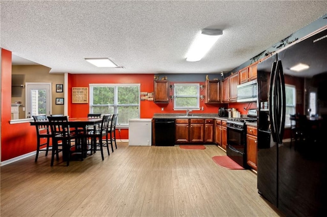 kitchen with light wood-style flooring, a sink, baseboards, black appliances, and brown cabinetry