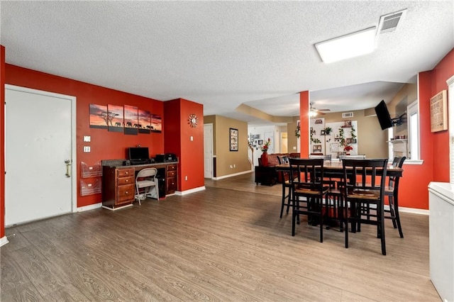 dining space with visible vents, ceiling fan, a textured ceiling, and wood finished floors