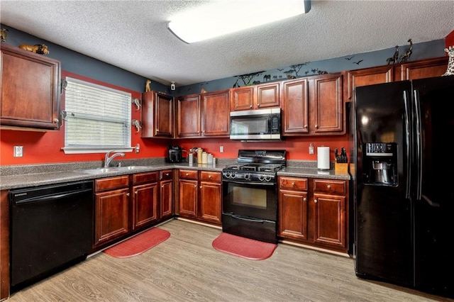 kitchen featuring a textured ceiling, light wood-style flooring, a sink, dark brown cabinets, and black appliances