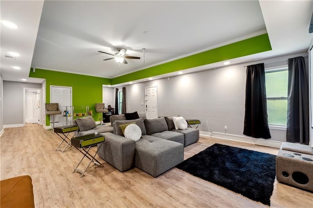 living room featuring crown molding, ceiling fan, light wood-type flooring, and baseboards