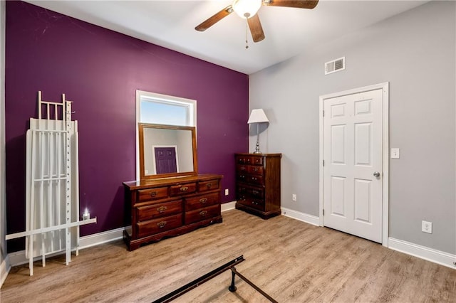 bedroom featuring baseboards, visible vents, ceiling fan, and light wood finished floors