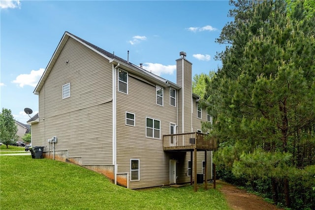 rear view of property featuring a deck, a yard, and a chimney