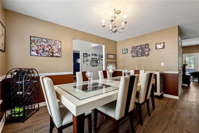 dining space featuring a textured ceiling, dark wood-type flooring, baseboards, and a notable chandelier