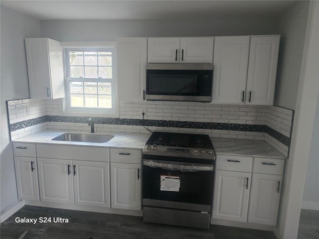 kitchen featuring dark wood-style flooring, a sink, white cabinets, appliances with stainless steel finishes, and tasteful backsplash