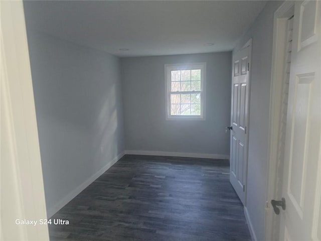 empty room featuring dark wood-type flooring and baseboards