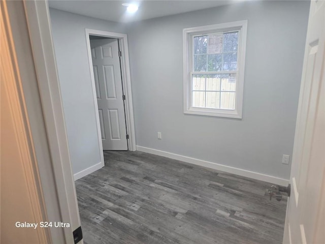 empty room with dark wood finished floors and baseboards