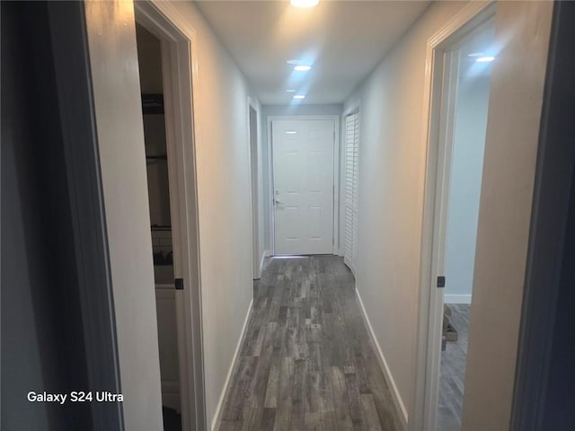 hallway featuring dark wood finished floors and baseboards