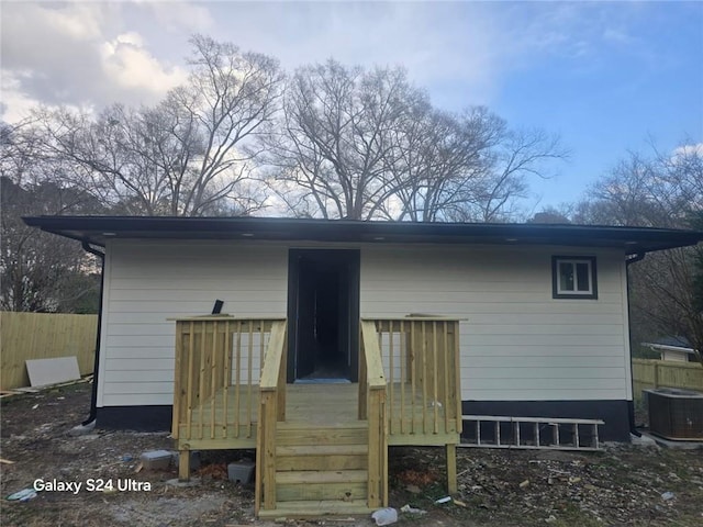 rear view of house with cooling unit, a wooden deck, and fence