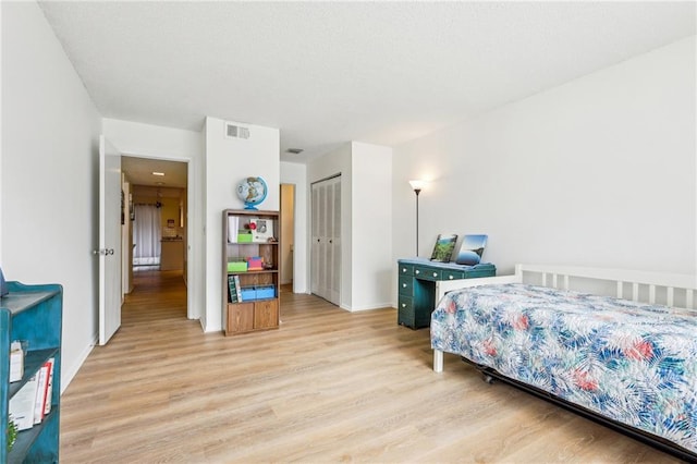 bedroom with light hardwood / wood-style floors and a closet