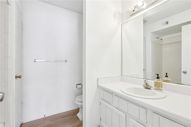 bathroom featuring vanity, hardwood / wood-style flooring, a shower, and toilet