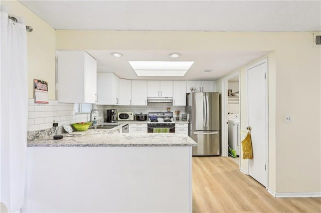 kitchen featuring sink, range with gas cooktop, stainless steel fridge, kitchen peninsula, and white cabinets