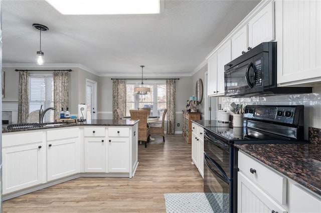 kitchen featuring tasteful backsplash, pendant lighting, black appliances, sink, and white cabinetry