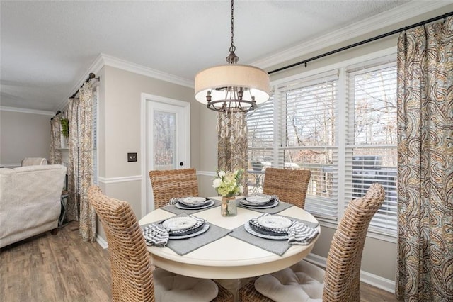 dining space featuring wood-type flooring, crown molding, and a healthy amount of sunlight