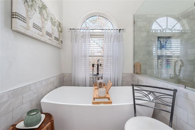 bathroom featuring tile walls and a bath