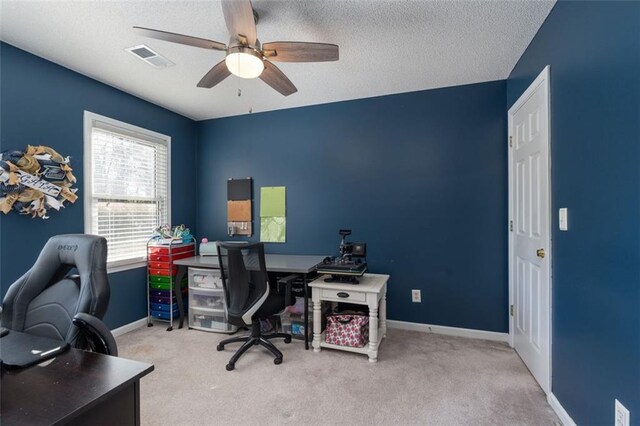 carpeted home office with ceiling fan and a textured ceiling