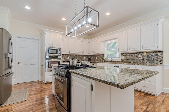kitchen with white cabinetry, appliances with stainless steel finishes, ornamental molding, and a center island